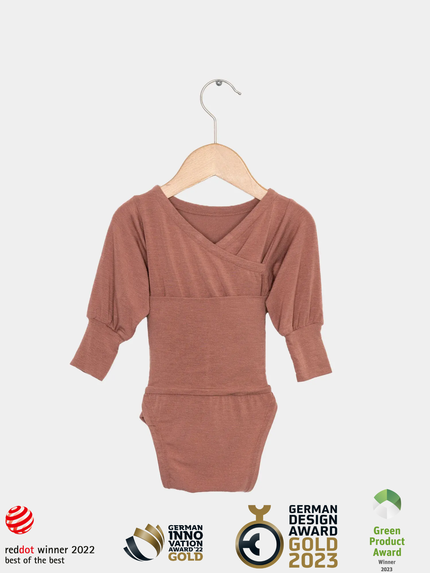 Loopbody Kaschmir-Mix - mitwachsender Babybody - Zimt: Ein langärmliger, wickelbarer Babybody ohne Knöpfe, aus weichem Kaschmir-Mix, auf einem Holzkleiderbügel. Prämiert mit mehreren Design- und Innovationspreisen.