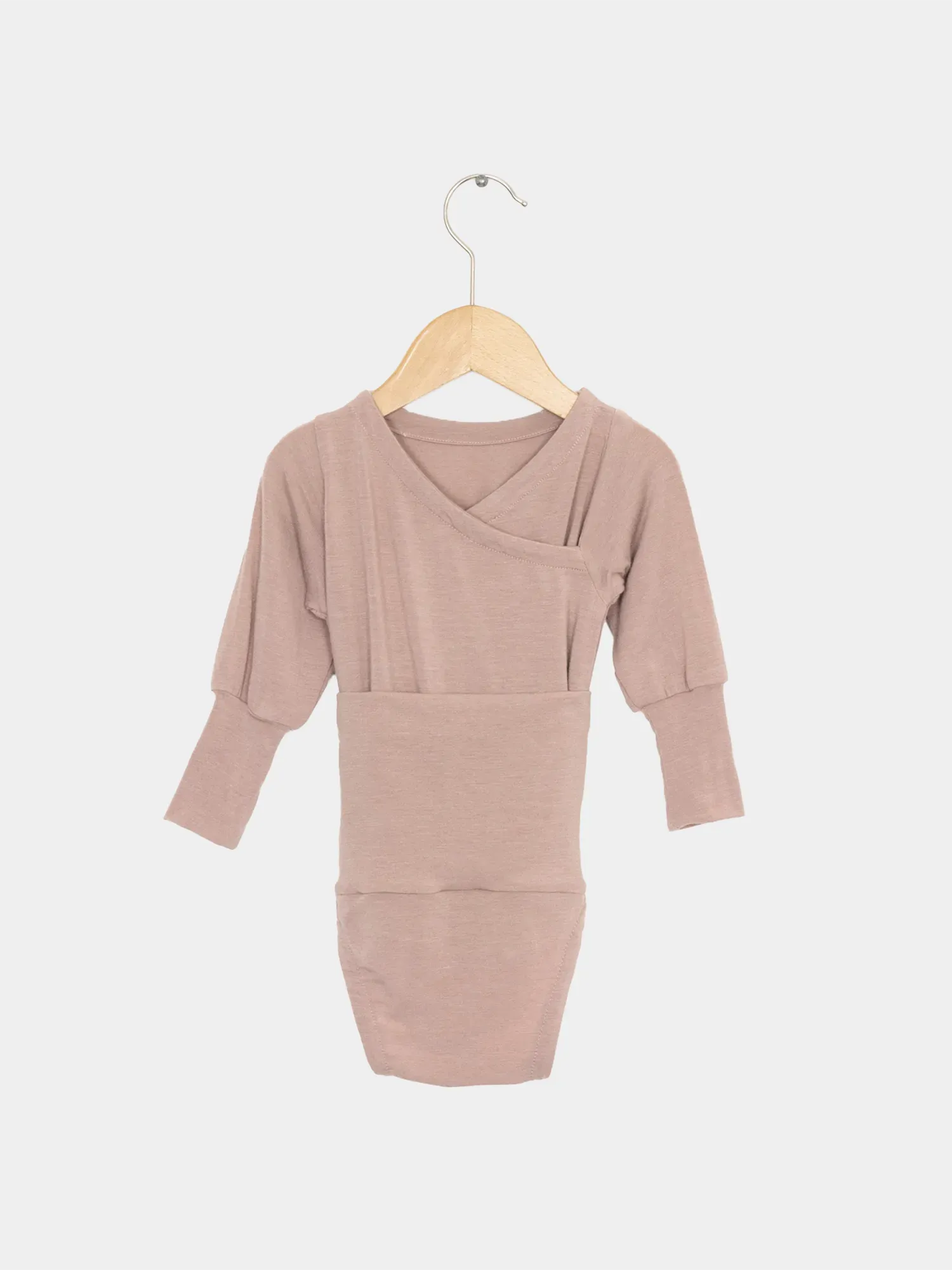 Loopbody Kaschmir-Mix - Puder: Langarm-Wickelbody mit kimonoartigem Frontdesign, weicher Kaschmir-Micromodal-Mix, ohne Knöpfe, auf Holzkleiderbügel hängend, bietet Komfort und Mitwachsen für Babys.