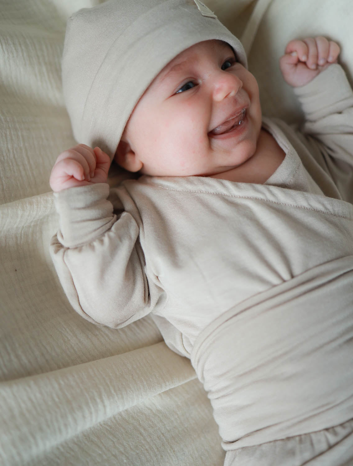 Baby im Loopbody Kaschmir-Mix - Sand, trägt einen supersoften, knopflose Langarmbody, der den Bauch umschließt und mitwächst, für extra Wärme und Komfort, ideal für Neugeborene. Erstausstattung Baby und Baby Geschenk zur Geburt.