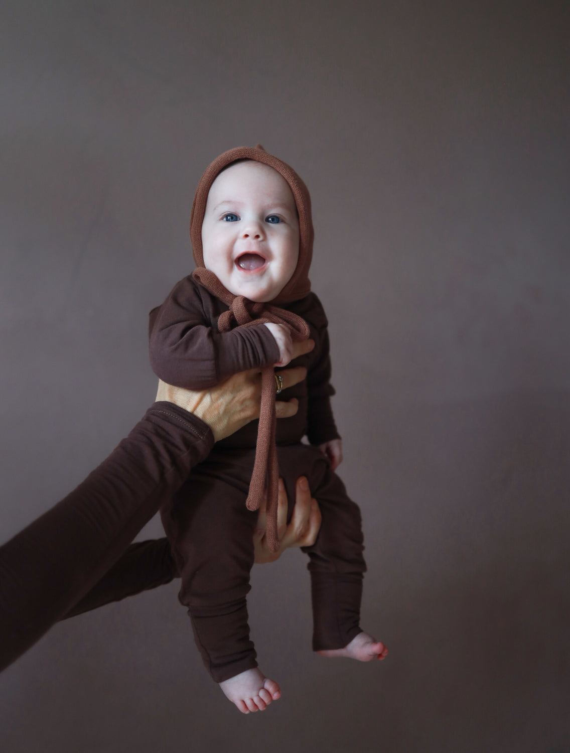 Erstausstattung Babys. Baby in einem Loopbody Kaschmir-Mix, getragen von einer Person. Der Body ist knopflos und bietet Komfort und wächst mit, ideal für Babys. ideale Baby Geschenke