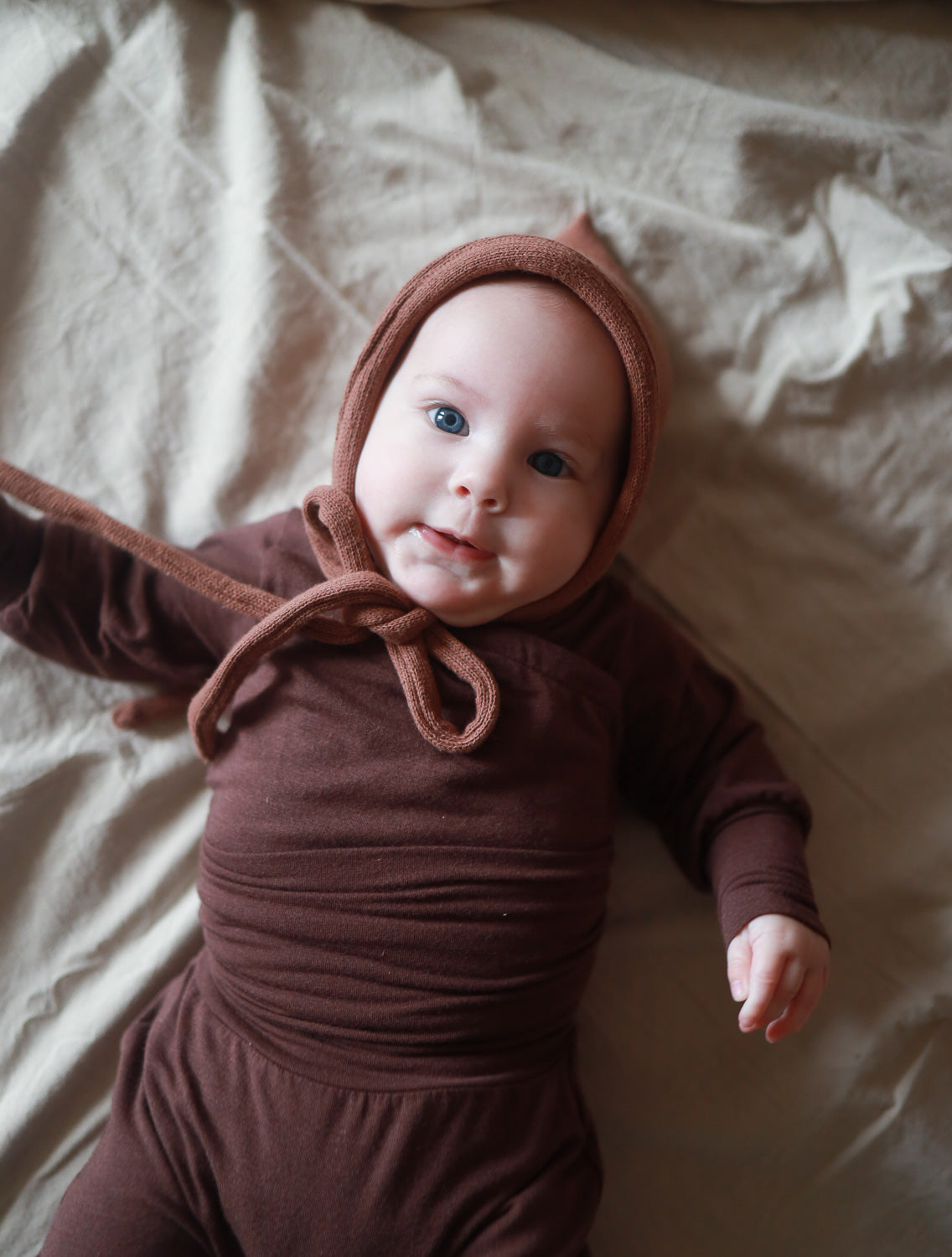 Baby liegt auf einer Decke, trägt den Loopbody Kaschmir-Mix - Malve von PETIT COCHON, ohne Knöpfe, weich und anpassungsfähig, ideal für Komfort und Wärme. Baby Body für Erstausstattung Baby.