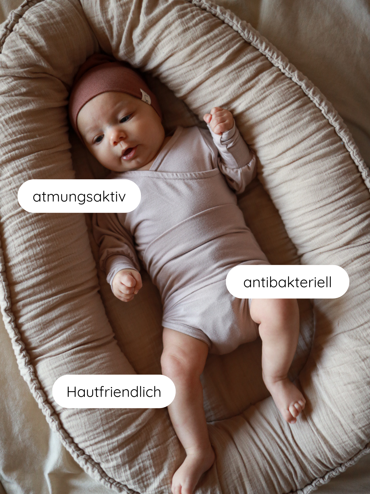 Baby liegt in einem weichen Nest, gekleidet in einem Loopbody Bambusviskose - Cremepuder. Text beschreibt Stoffmerkmale: atmungsaktiv, antibakteriell, hautfreundlich. Ideal für Komfort und Bewegungsfreiheit.