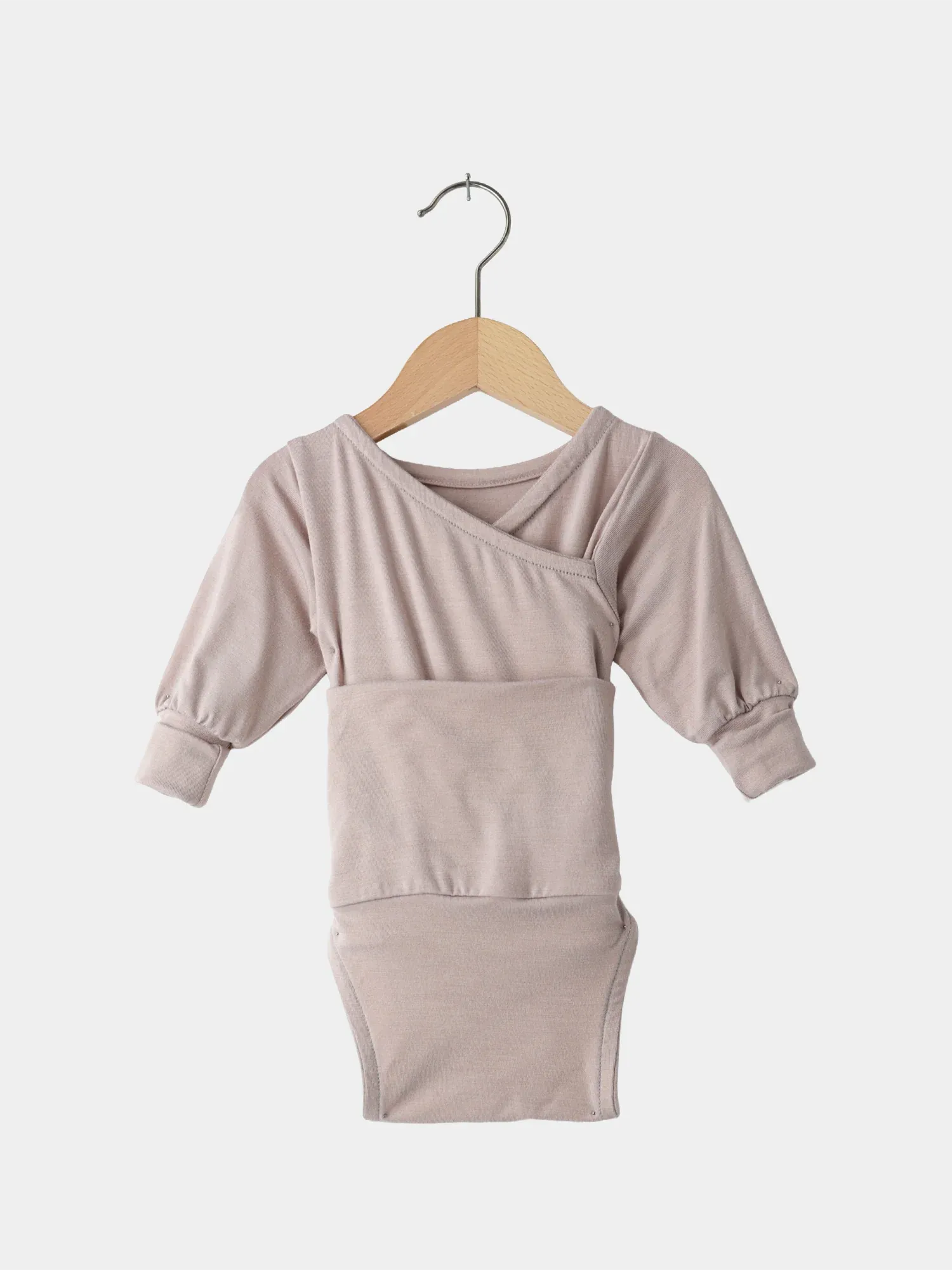 Loopbody Bambusviskose - Cremepuder: Langärmeliger Babybody in neutralem Beige mit Kimono-Überschlag und Druckknopfverschluss, hängend an einem Holzkleiderbügel; weich, atmungsaktiv und antibakteriell für ultimativen Komfort.
