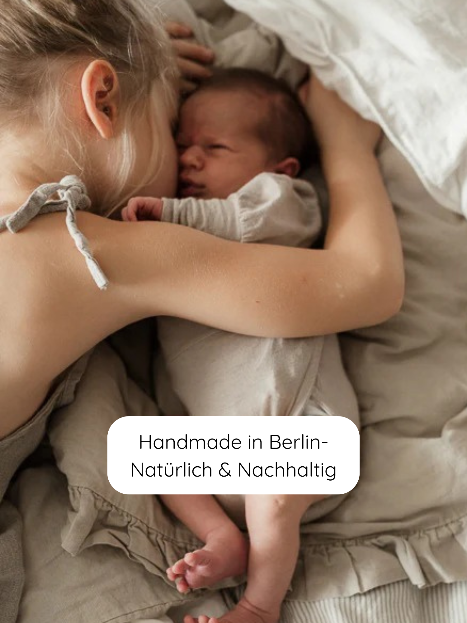 Eine junge Mutter kuschelt im Bett mit einem Neugeborenen, das den Loopbody Bambusviskose - Natur trägt, handgefertigt in Berlin aus nachhaltigen Materialien, atmungsaktiv und mitwachsend, ideal für Stoffwindeln.