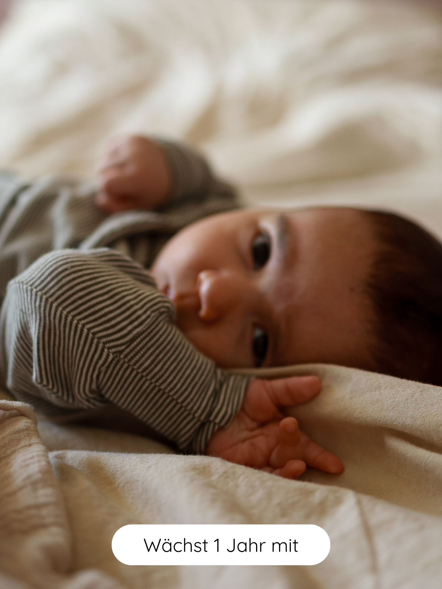 Baby in einem Loopbody Bio-Baumwolle - Ringel Maus: grauweiß gestreifter Langarm-Romper. Label: „Wächst 1 Jahr mit“. Nachhaltige, langlebige Kinderkleidung von PETIT COCHON aus Berlin.