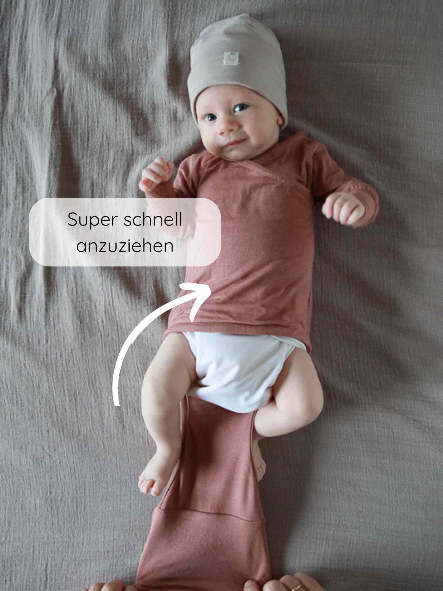 Ein Baby trägt den Loopbody Kaschmir-Mix - mitwachsender Babybody - Zimt, während Erwachsene die Wickelklappe anlegen. Text zeigt: Super schnell anzuziehen, was die einfache Handhabung betont.