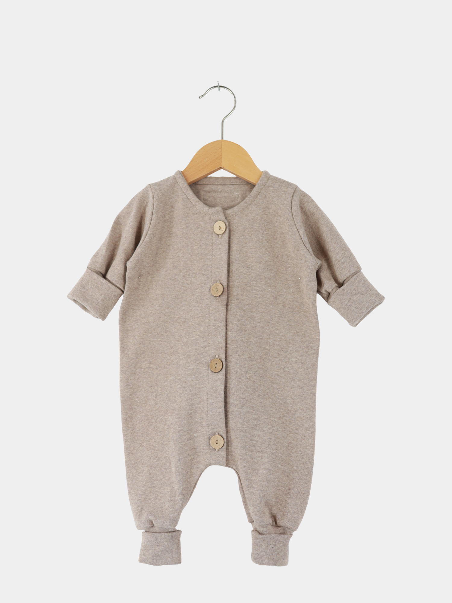 Mini Overall Feinstrick - Hafer Meliert, langärmeliger Baby-Strampler aus weichem, meliertem Feinstrick-Jersey mit Holzknöpfen und umschlagbaren Bündchen an Ärmeln und Beinen, auf einem Holzkleiderbügel hängend.