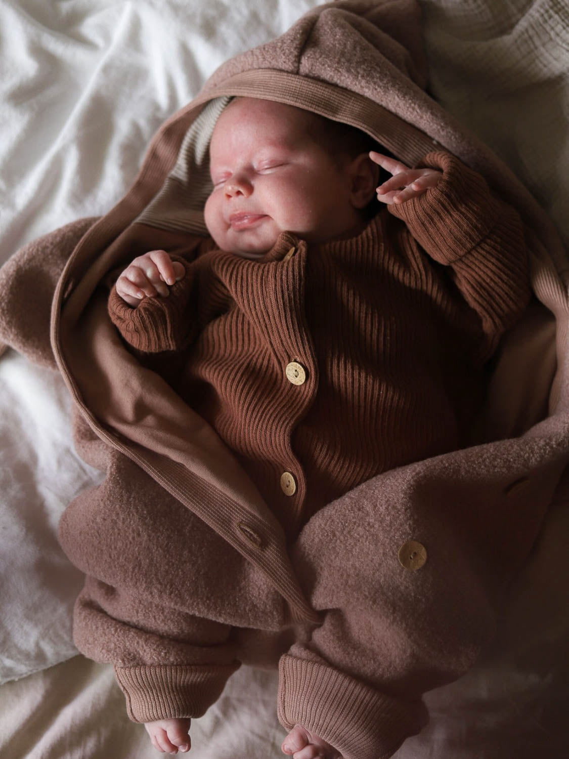 Schlafendes Baby im Mini Overall Rippstrick - Nougat aus recycelter Baumwolle, kuschelig und komfortabel, idealer Strampler für Neugeborene und Kleinkinder.