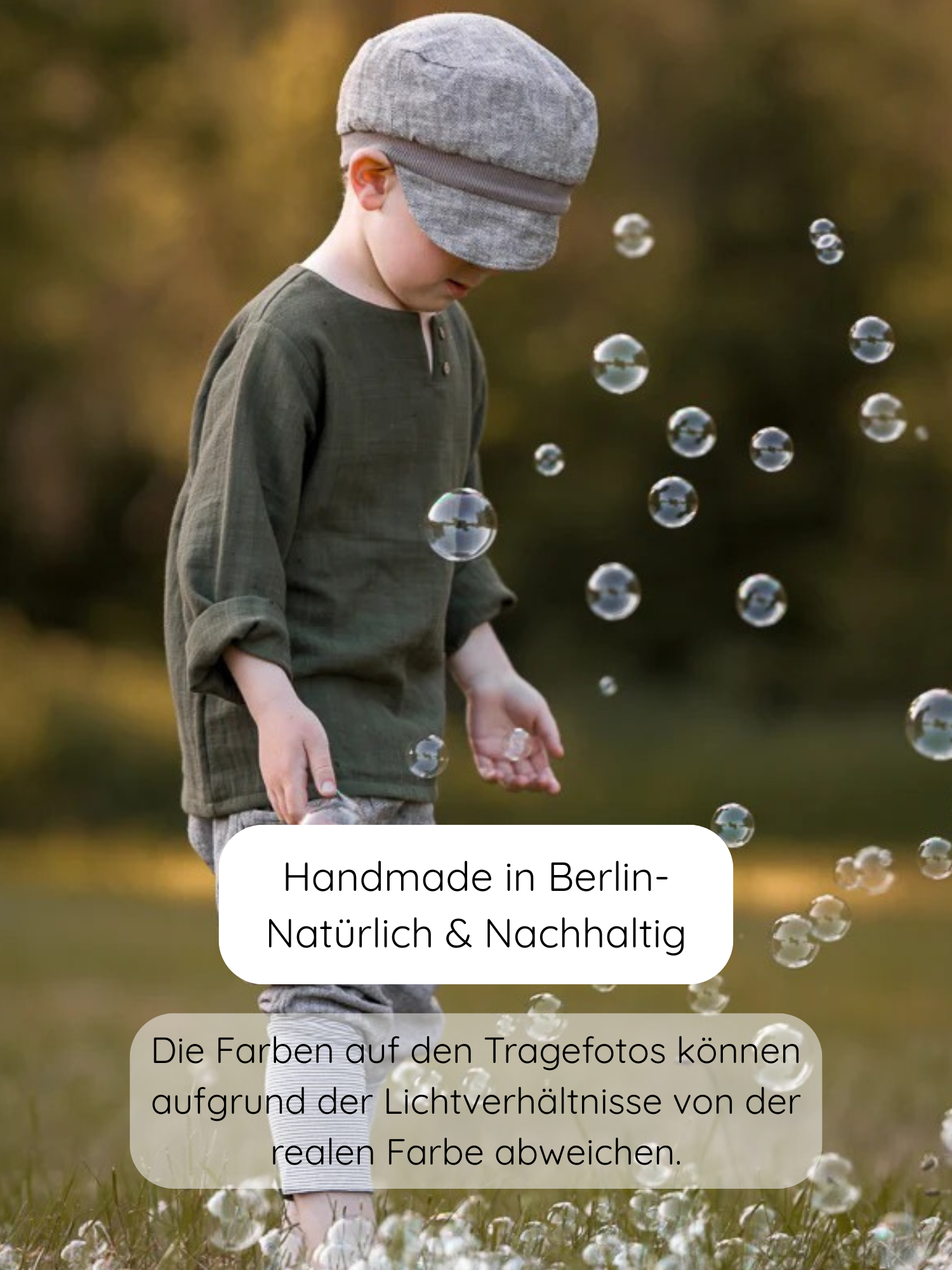 Kleinkind im Freien mit Michelmütze Fischgrat Maus, spielt mit Seifenblasen. Die handgefertigte Mütze aus Baumwoll-Fischgrat bietet Schutz und wächst dank verstellbarem Zugband mit. Ideal für empfindliche Kinderköpfe.