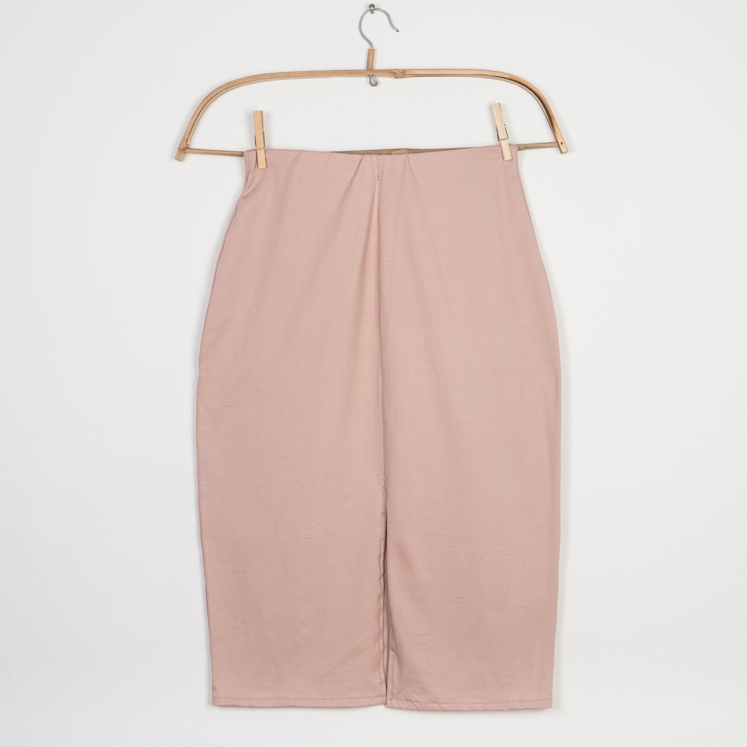 Bleistiftrock Jersey Puder Gr. L: Einfach geschnittener Midirock in sanftem Blushton, gerade Form, präsentiert an hölzernem Bügel. Zustand neu, mit zwei kleinen Flecken hinten.