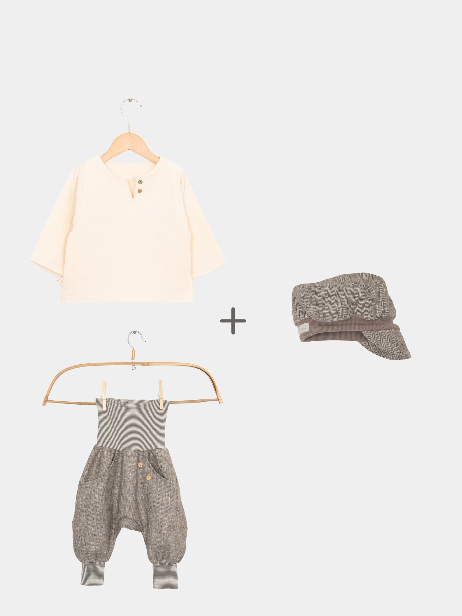 Set Fischgrat Maus: Ein weißes Hemd hängt auf einem Kleiderbügel, kombiniert mit einerMichelmütze. Daneben Knickerbocker mit Knöpfen, präsentiert in modischem Design. Nachhaltige Kinderkleidung aus Berlin.