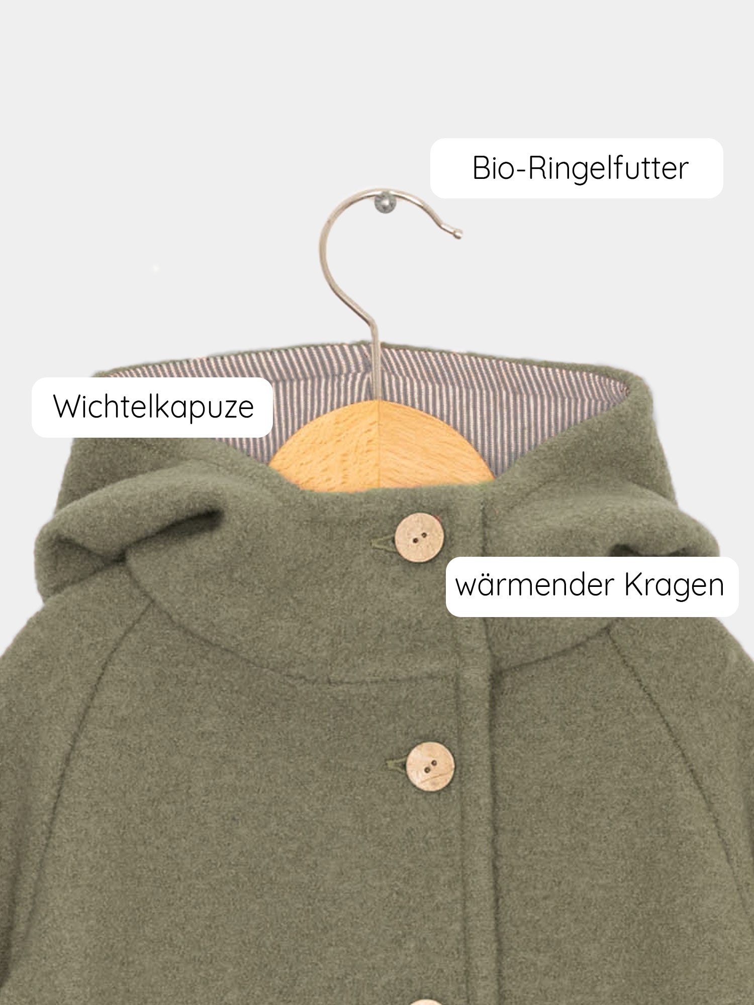 Wichteljacke Wollwalk - Pistazie auf einem Kleiderbügel, zeigt Knöpfe und einen Metallhaken. Die Jacke bietet Bewegungsfreiheit und ist mit Bio-Baumwoll-Jersey gefüttert, ideal für Kinder. nachhaltige Kinderkleidung aus Wollwalk