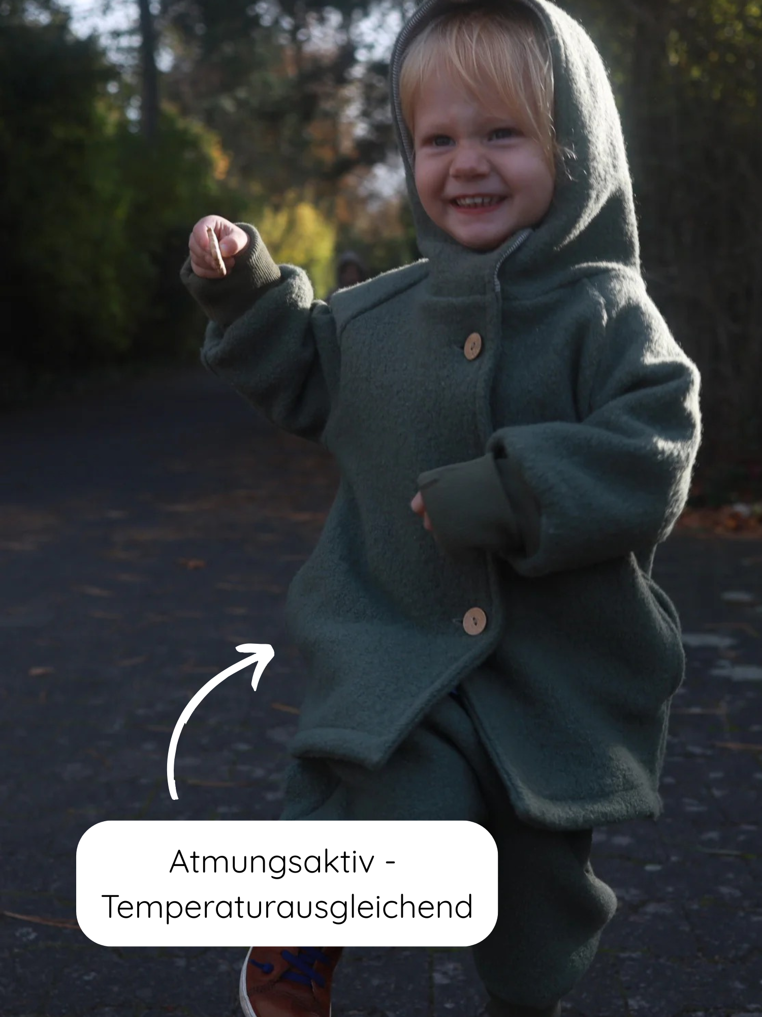 Kleinkind im Wollwalk-Wichteljacke Pistazie, atmungsaktiv und temperaturausgleichend, mit Holzknöpfen, auf einem Weg laufend. Ideal für Herbst, Winter und Frühling.