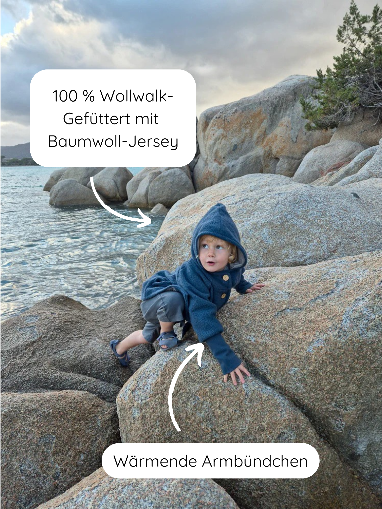 Kleinkind klettert auf Küstenfelsen, trägt die Wichteljacke Wollwalk - Marine mit Kapuze, gefüttert mit Baumwoll-Jersey. Jacke hat wärmende Armbündchen, ideal für Herbst, Winter und Frühling.