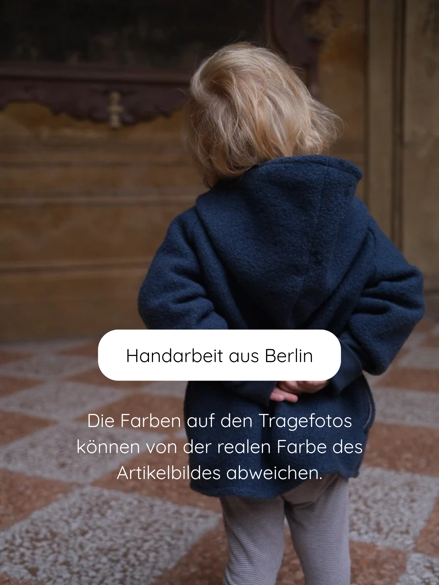 Ein Kind trägt eine Wichteljacke Wollwalk - Marine, handgefertigt in Berlin. Die dunkelblaue Kapuzenjacke ist warm gefüttert und eignet sich ideal für kühle Jahreszeiten.