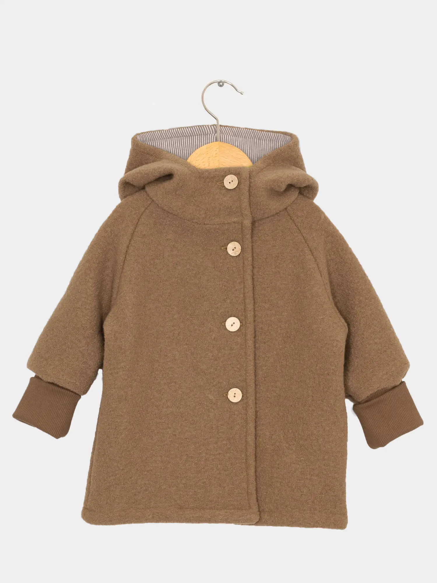 Wichteljacke Wollwalk - Kamel: Kleine braune Wolljacke mit Kapuze und Ohren, hängend an Holzbügel. Vier runde Holzknöpfe vorne, lange Ärmel mit umschlagbaren, gerippten Bündchen.