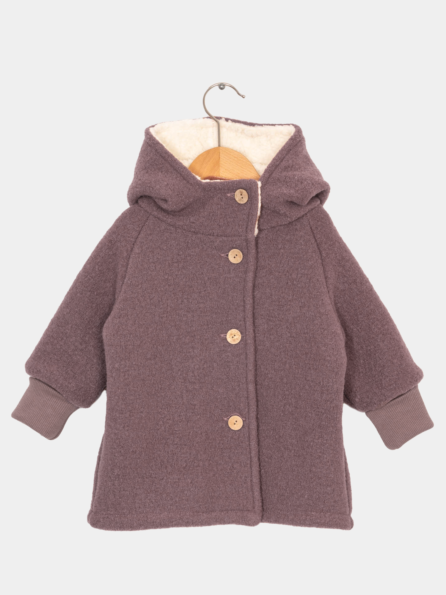 Teddy-Wichteljacke Wollwalk - Malve auf einem Haken hängend, zeigt Details wie gestrickte Ärmel und Knöpfe, ideal für kalte Wintertage dank Teddyfutter.
Wollwalkjacke und Winterjacke für Kinder. Handgenäht in Berlin