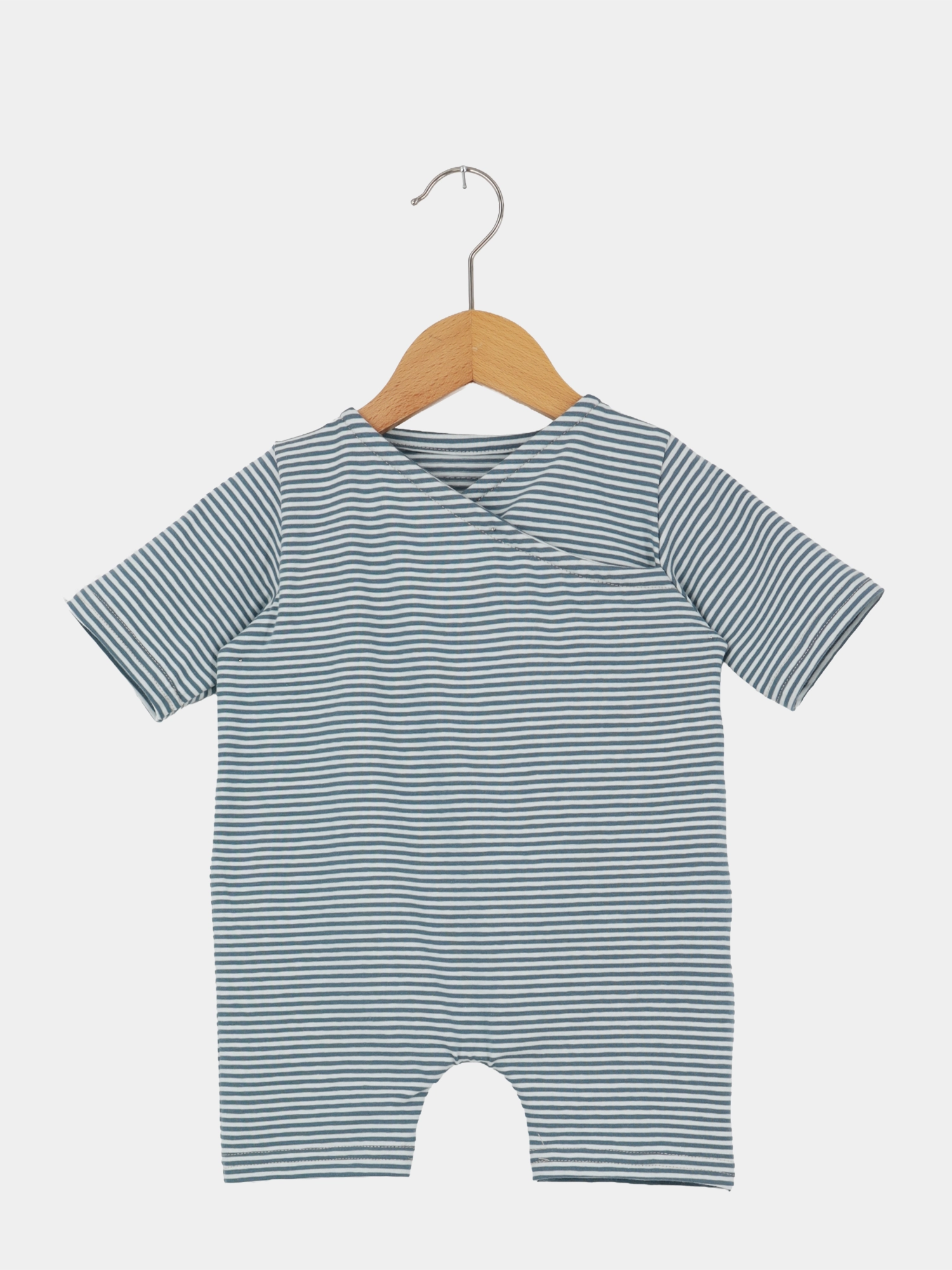 Wickel Overall Baumwolle - Ringel Taube: Ein kurzärmeliger Baby-Body mit schmalen blau-weißen Streifen, aus doppellagigem Bio-Musselin, hängend an einem Holzkleiderbügel, ideal für warme Tage.