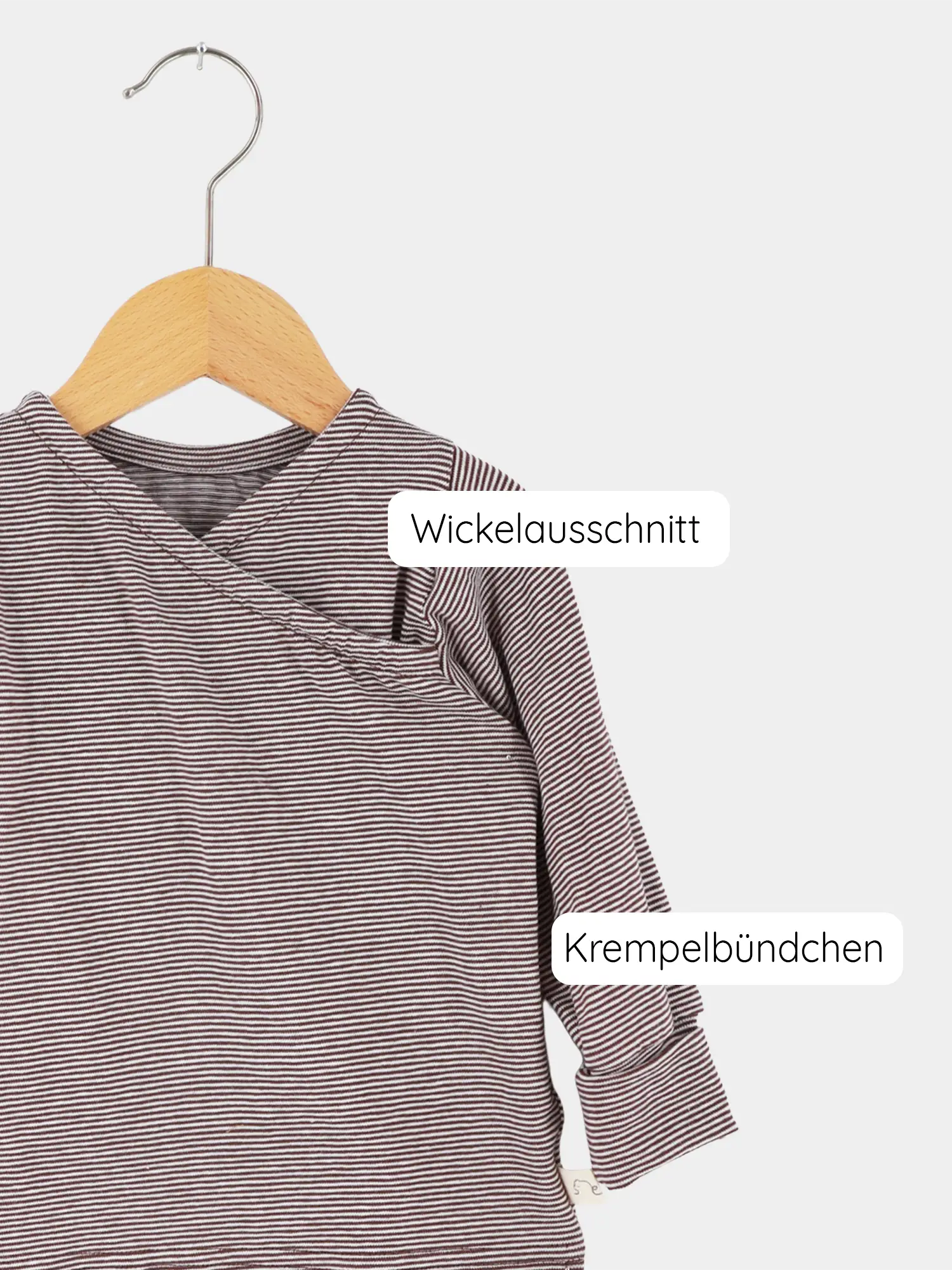Wickelshirt aus Bio-Baumwolle - Ringel Schoko mit Wickelausschnitt und krempelbaren Bündchen. Langarmshirt auf Holzkleiderbügel, zeigt dezentes Streifenmuster, ideal für empfindliche Babys, unkompliziert und wachstumsfähig.