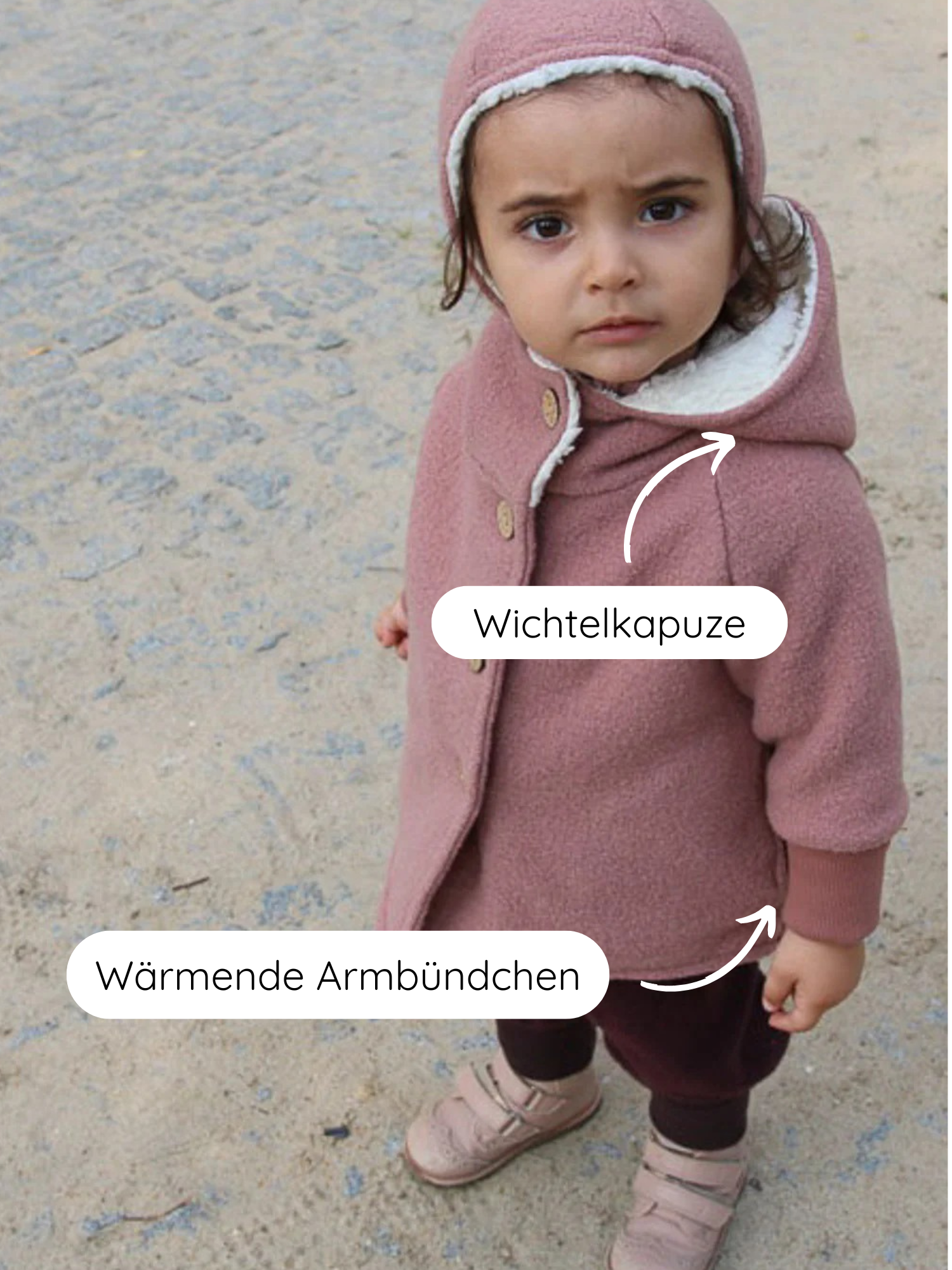 Kleinkind in Winter Wichteljacke Wollwalk - Puder mit spitzer Kapuze, fleecegefüttert, trägt dunkle Leggings und rosa Schuhe. Jacke mit wärmenden Bündchen und Velcro-Schuhen auf sandigem Pflaster.
