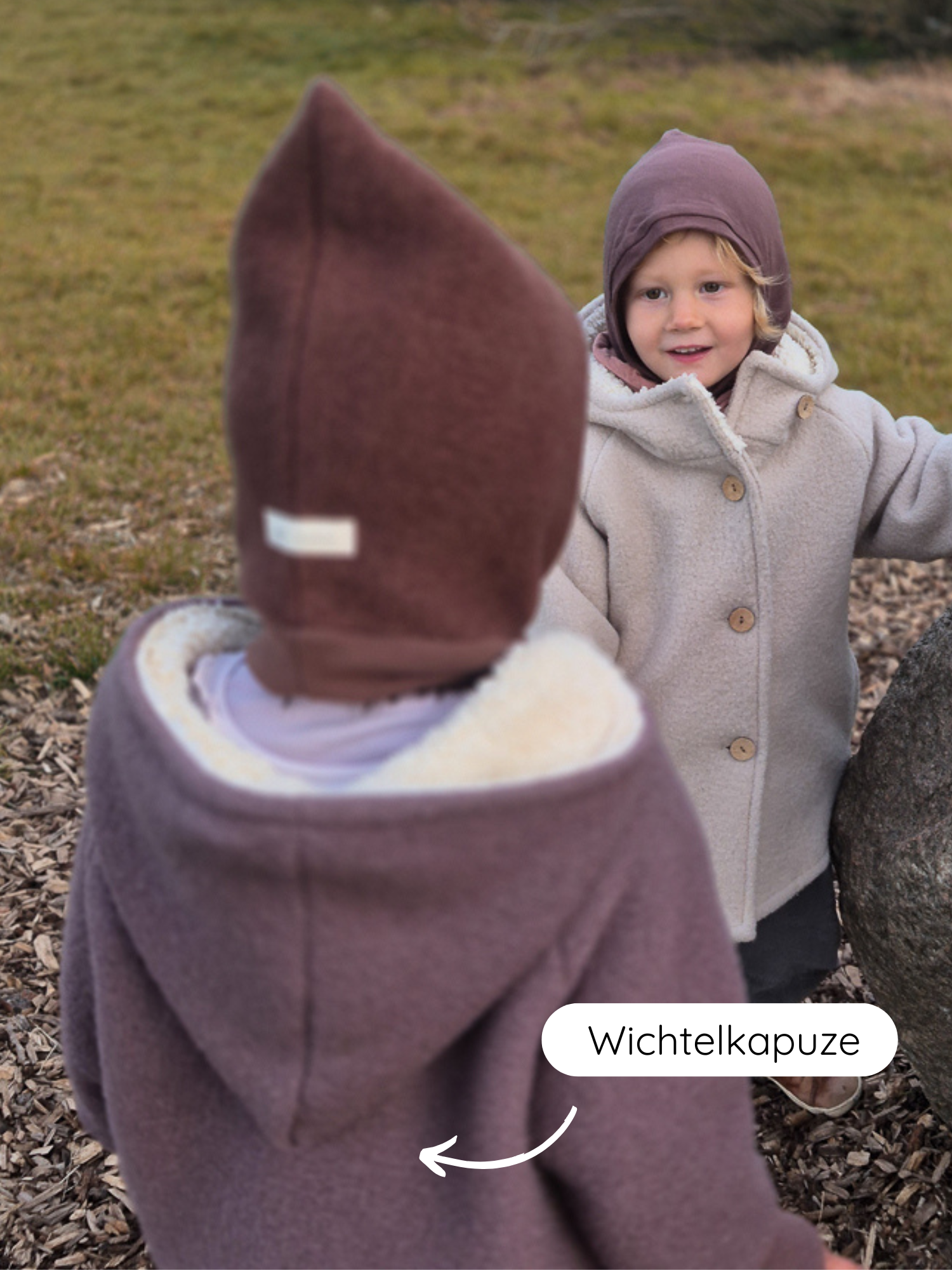 Zwei Kinder tragen die Winter Wichteljacke Wollwalk mit Teddyfutter - Malve, eine zeigt die spitze Wichtelkapuze, während die andere den kuscheligen, wärmenden Look von vorne präsentiert.