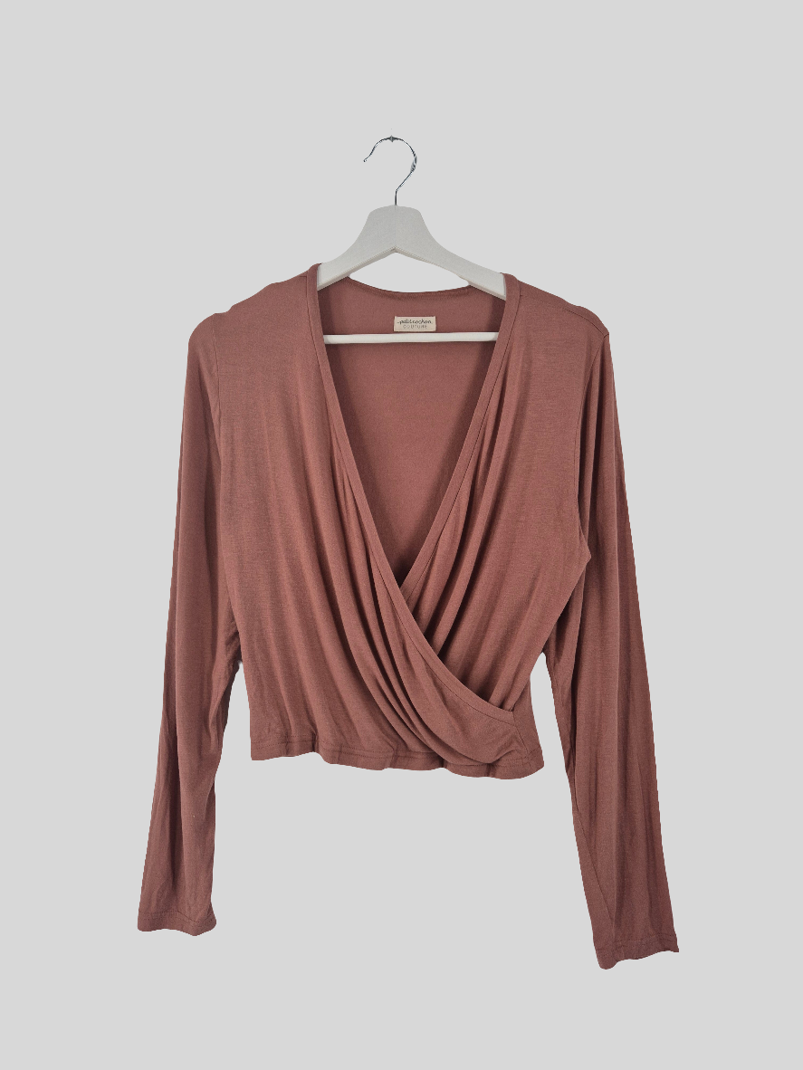 Wickelshirt Kaschmir-Mix Zimt Gr. M, langärmlig, mit tiefem Ausschnitt und kürzerem Schnitt, wie neu. Hängt an einem weißen Bügel vor einem schlichten Hintergrund.