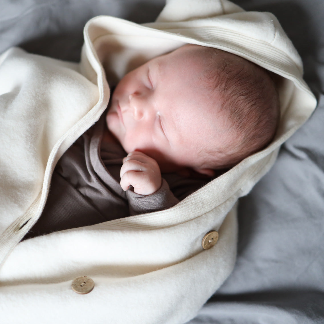 Baby schläft auf Decke. Trägt Kuschelanzug und Baby Body. Der Loopbody ist das perfekte Baby Geschenk. Nachhaltig, mitwachsend und bequem.