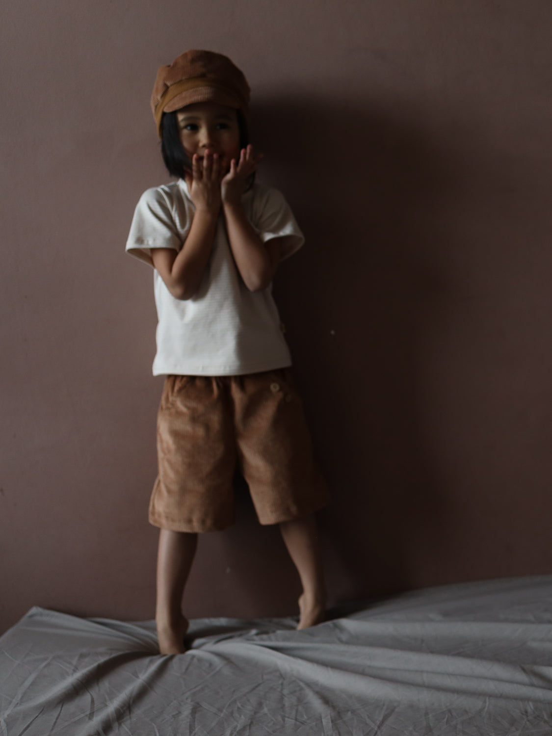 Kind trägt Kurze Buxe Breitcord - Weizen, eine weiche, strapazierfähige Cordhose mit lockerem Schnitt und elastischem Bund, ideal für aktive Kinder. Perfekt für Spielplatz und Alltag. Fair in Berlin gefertigt.