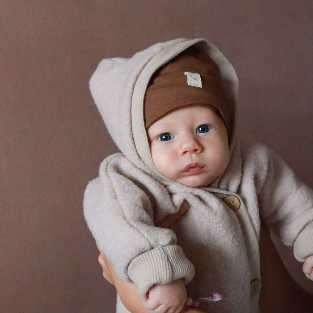 Baby trägt Wollwalk Overall von Petit Cochon. Nachhaltige Kinderkleidung und Baby Erstausstattung in Berlin genäht.