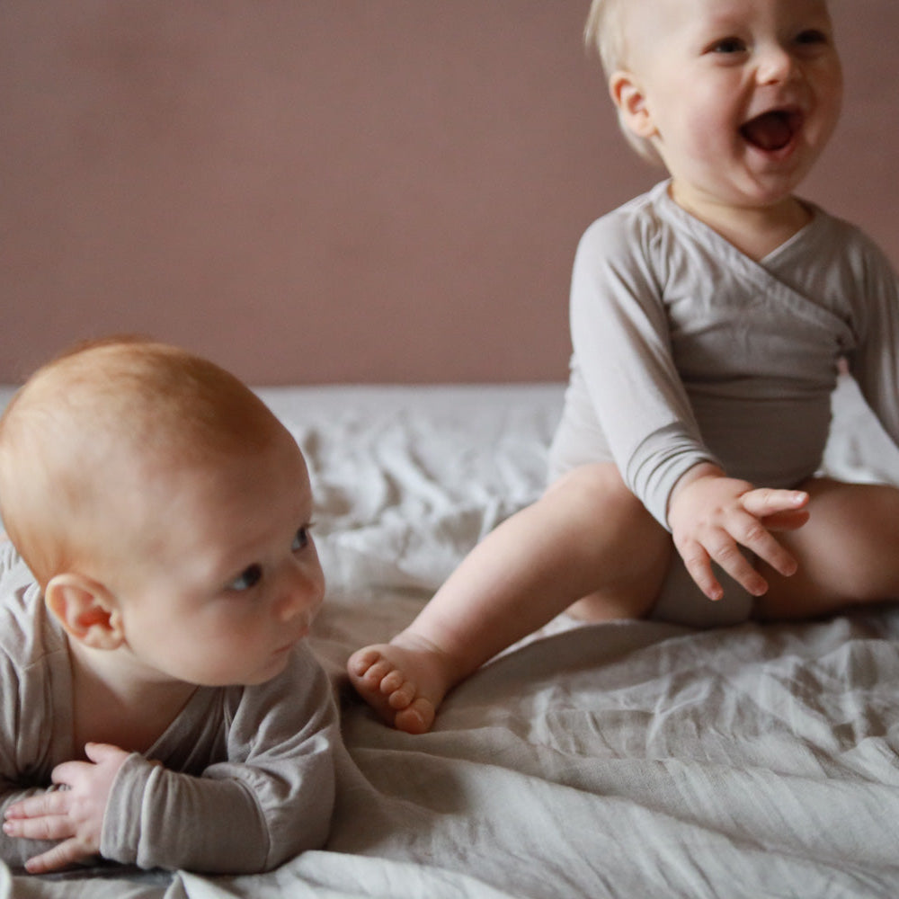 Zwei Babys tragen Loopbodys. Nachhaltige Baby Bodys, clever und schlicht ohne Knöpfe. Perfekte Baby Erstausstattung.
