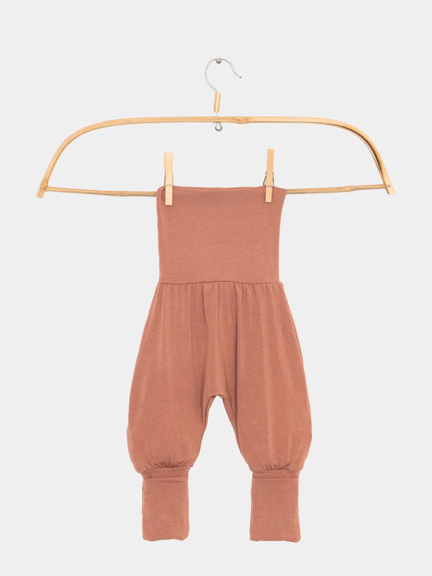 Babyknicker Kaschmir-Mix - Zimt auf einer Schaukel hängend, zeigt die weichen, umklappbaren Bündchen. Perfekt für Babys, um Wärme und Komfort zu bieten, passend zum Loopbody aus Kaschmir-Mix.