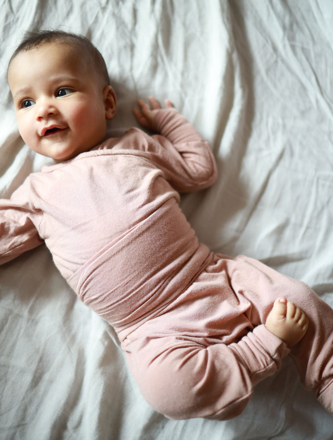 Baby in Kaschmir-Mix Babyknicker mit Klappbündchen auf Decke liegend, ideal für Wärme und Komfort, passend zum Loopbody für Neugeborene.