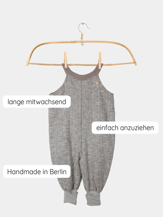 Schlupflatzhose aus Fischgrat auf einem Holzbügel präsentiert, zeigt robuste Leinen-Baumwoll-Mischung und Jerseybündchen mit feinen Streifen. Perfekt für Alltag und festliche Anlässe, handgenäht in Berlin.