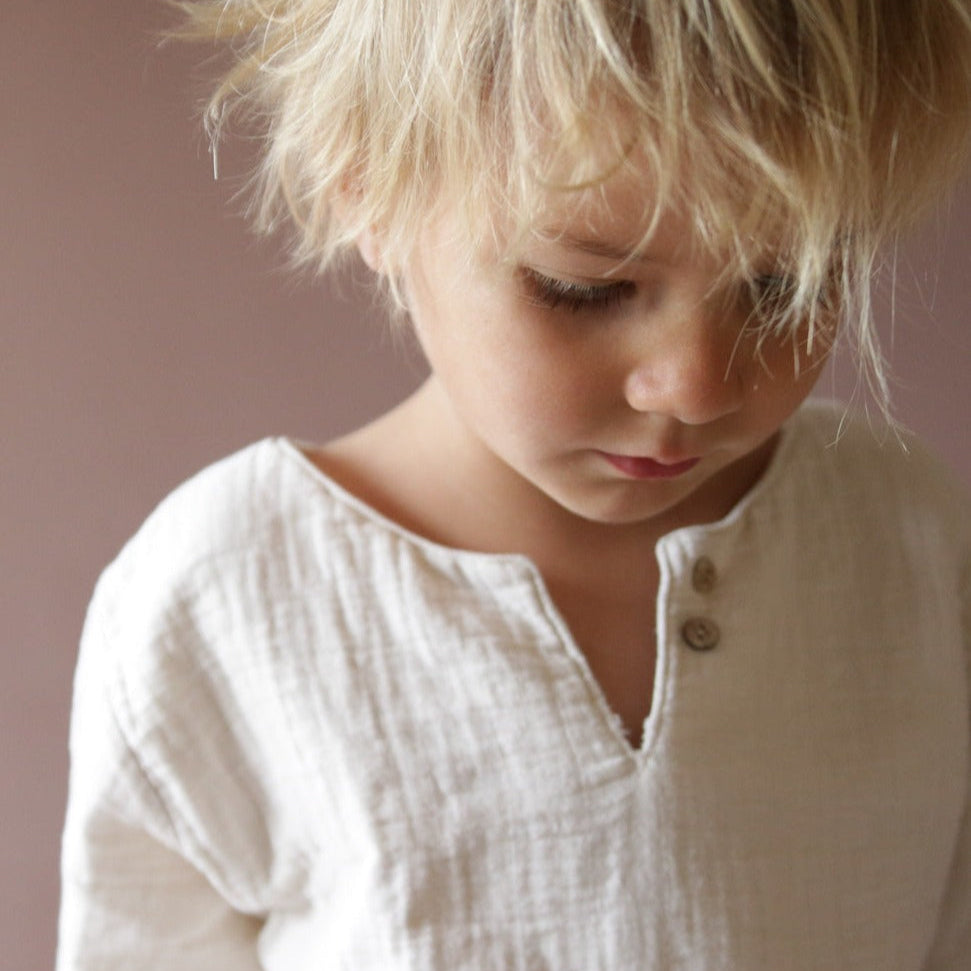 Kind trägt Musselinhemd, Hemdchen Musselin Natur. Die Kinderkleidung ist aus Bio-Baumwolle und ist atmungsaktiv und bequem.