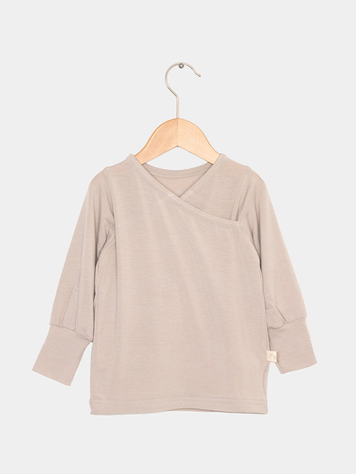 Wickelshirt aus Kaschmir-Mix - Sand auf Holzkleiderbügel, zeigt weiche, elastische Struktur und krempelbare Bündchen. Ideal als Shirt oder Unterhemd.