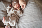 Ein Baby trägt Kleidung aus natürlichen Materialien, wie Wolle, Baumwolle und Leinen, was für seine empfindliche Haut wichtig ist. Warum Kleidung aus natürlichen Materialien für dein Baby so wichtig ist.