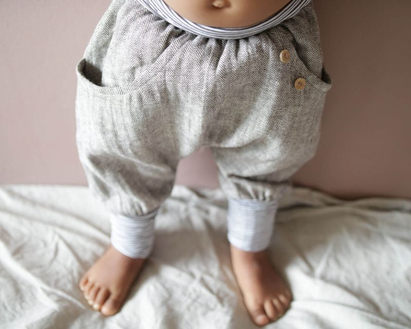 Nahaufnahme von Babybeinen in einer Knickerbocker Fischgrat von Petit Cochon. Geeignet für Babys und Kleinkinderkleidung.