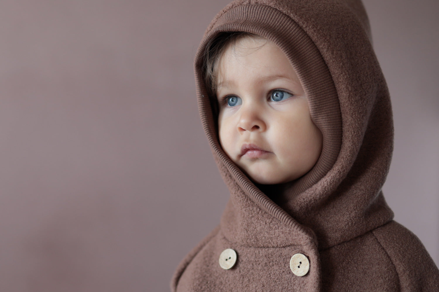 Ein Kind trägt eine Wollwalk Jacke für Kinder Nahaufnahme des Gesichts mit blauen Augen und Lippen, geeignet für Kleinkinder oder Jungen.