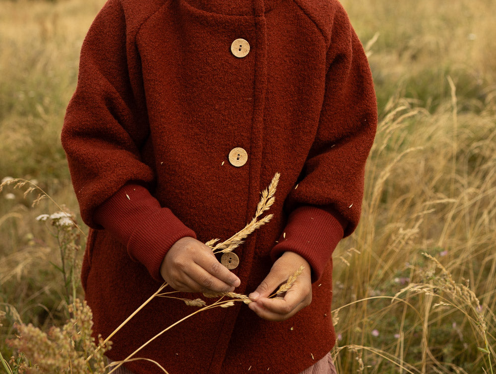 Ein Kind trägt eine Wollwalk Jacke für Kinder Nahaufnahme des Gesichts mit blauen Augen und Lippen, geeignet für Kleinkinder oder Jungen.