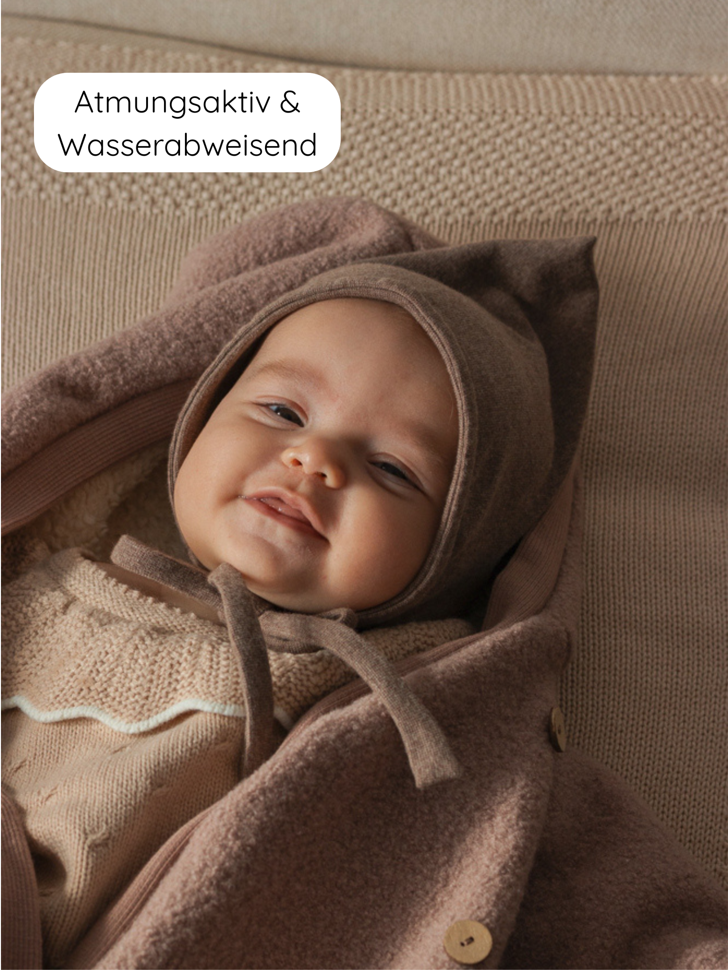 Winter Wollwalk Overall mit Teddyfutter- Puder: Ein lächelndes Baby in einem atmungsaktiven, wasserabweisenden Overall mit brauner Mütze und passendem Strick, ideal für kalte Tage.