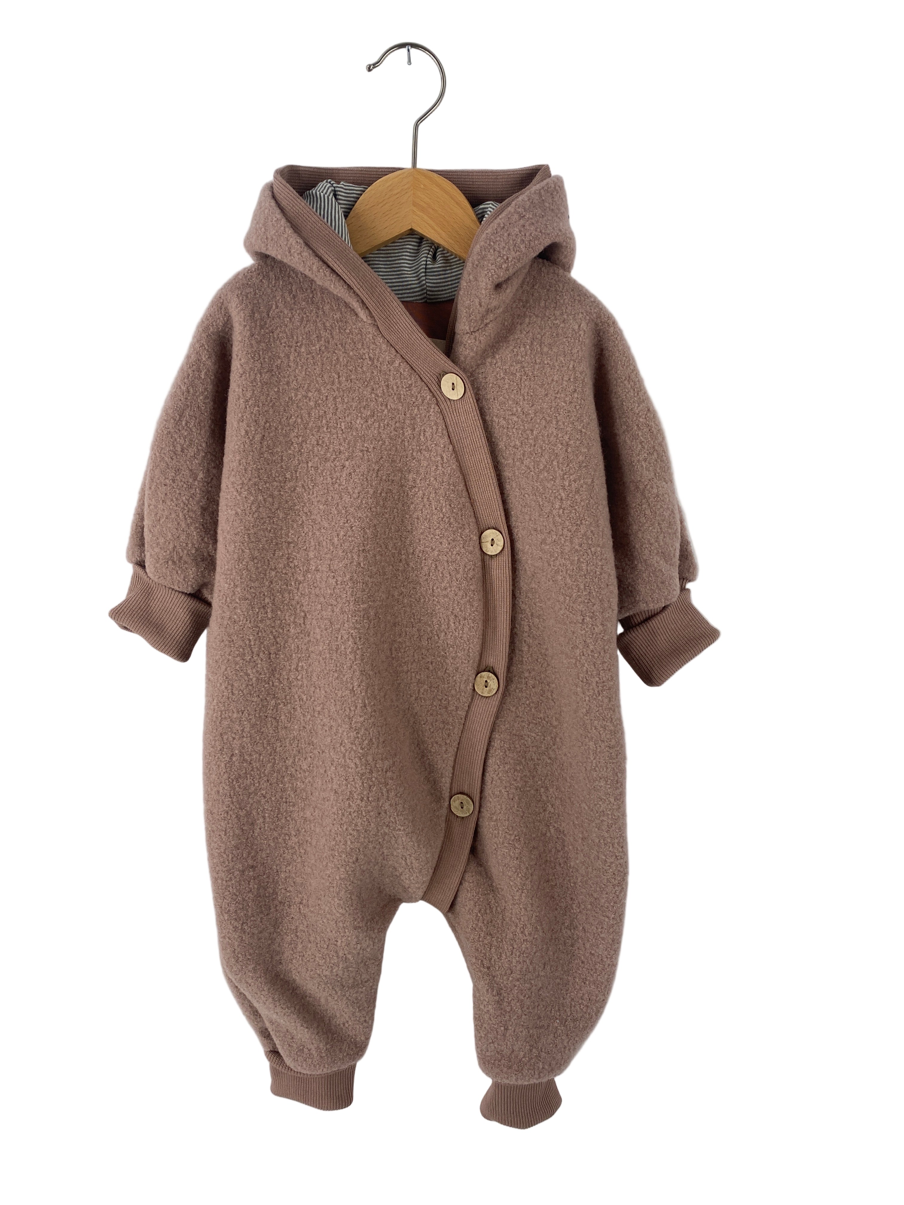 Kopie Kuschelanzug Wollwalk Puder Gr 6M: Ein kuscheliger Einteiler aus teddyfleeceartigem Stoff mit Kapuze, Holzknöpfen und gerippten Bündchen. Leichter Stofffehler hinten am Bein.