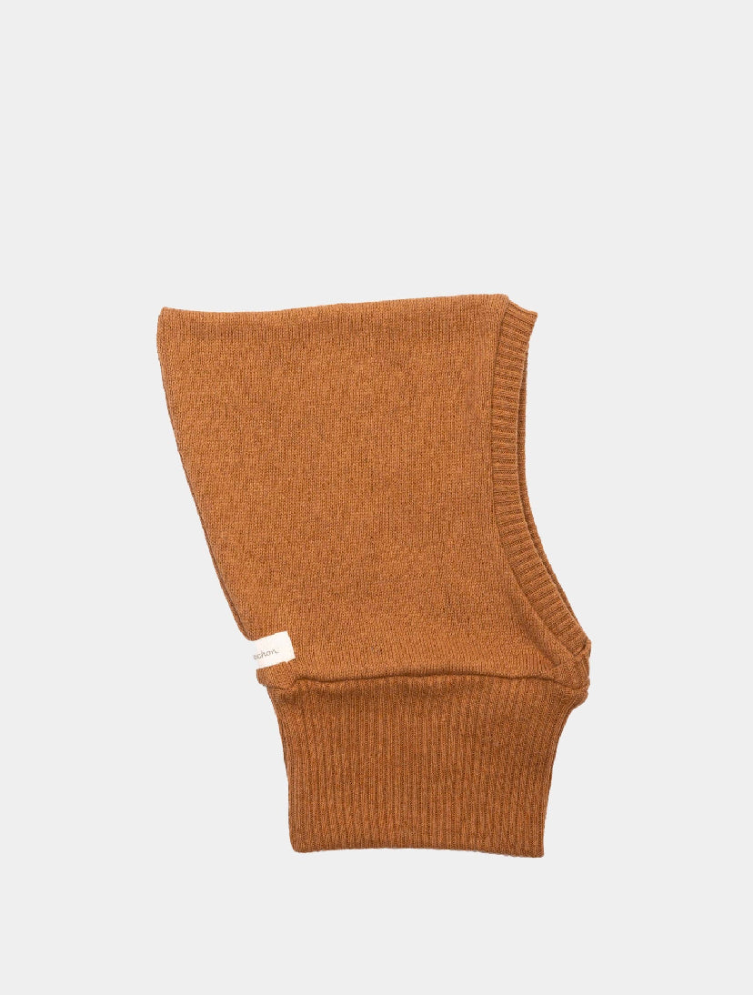 Schlupfmütze Strick Sahara Gr 0M-6M: Rustbraune, mittelgewichtige Strickhaube mit geripptem Rand und Gesichtsausschnitt, flach ausgelegt. Ein kleines Stoffetikett ist an der Seitennaht angebracht. Zustand: neu.