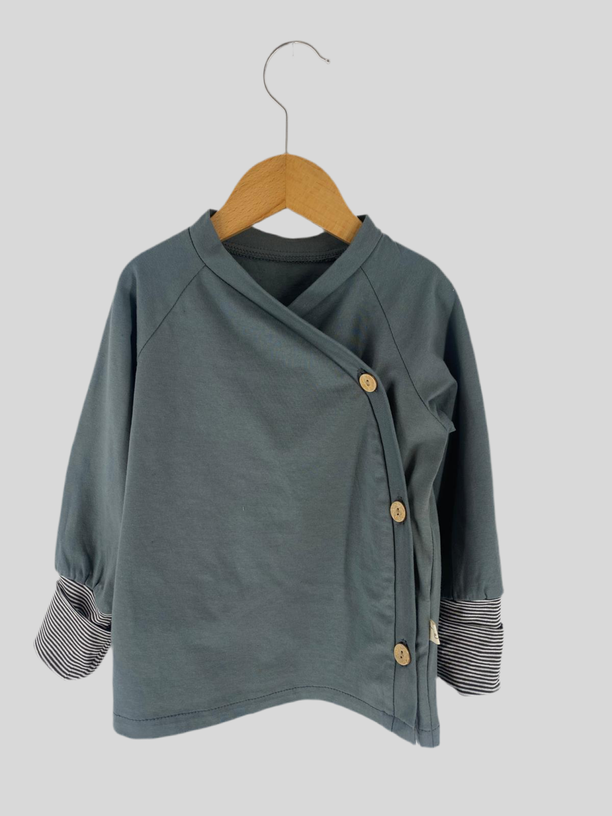 NEU Schlüttli Bio-Jersey Taube Gr 2Y, ein graues Hemd mit Knöpfen, zeigt feine Details und hochwertige Verarbeitung, ideal für lässige Anlässe. Perfekter Sitz mit langen Ärmeln.
