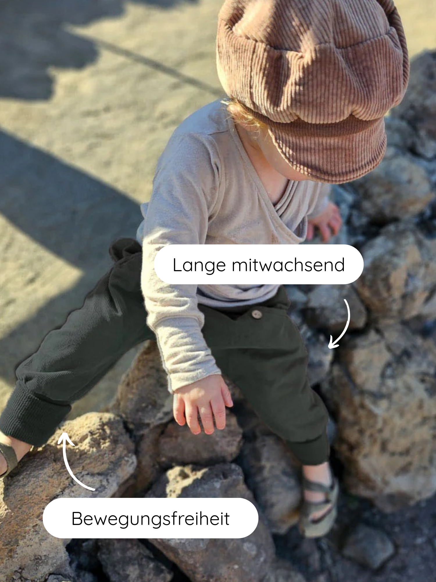 Kleinkind in Knickerbocker Feincord - Avocado, sitzt auf Felsen. Weiche, flexible Hose mit elastischem Bund, ideal für Bewegungsfreiheit. Cord-Kappe ergänzt das Outfit.