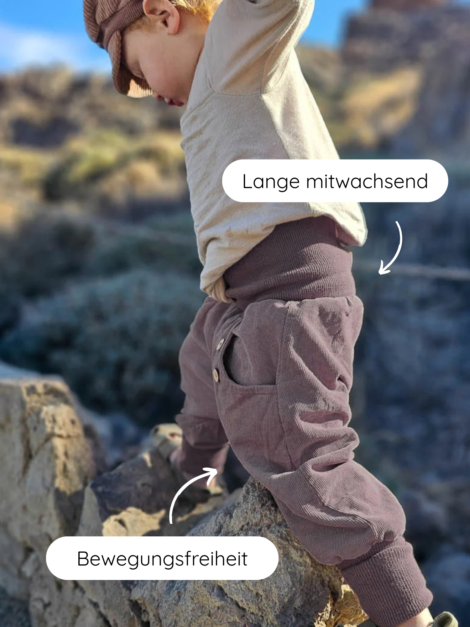 Kleinkind klettert auf Felsen in Knickerbocker Feincord - Malve, zeigt lang mitwachsende, braune Cordhose mit hohem Bund und weitem Schnitt für Bewegungsfreiheit. Perfekt für aktive Entdecker.