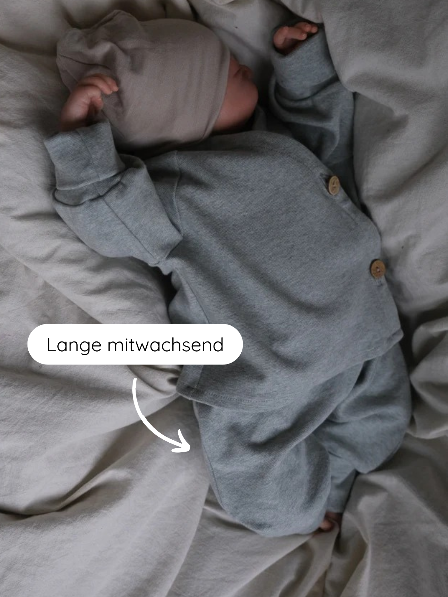 Babyknicker Feinstrick - Mint Meliert: Ein Neugeborenes trägt ein graues Strickset mit taupefarbener Mütze. Ein Pfeil zeigt auf die verstellbare Länge der Hose, die mitwächst.