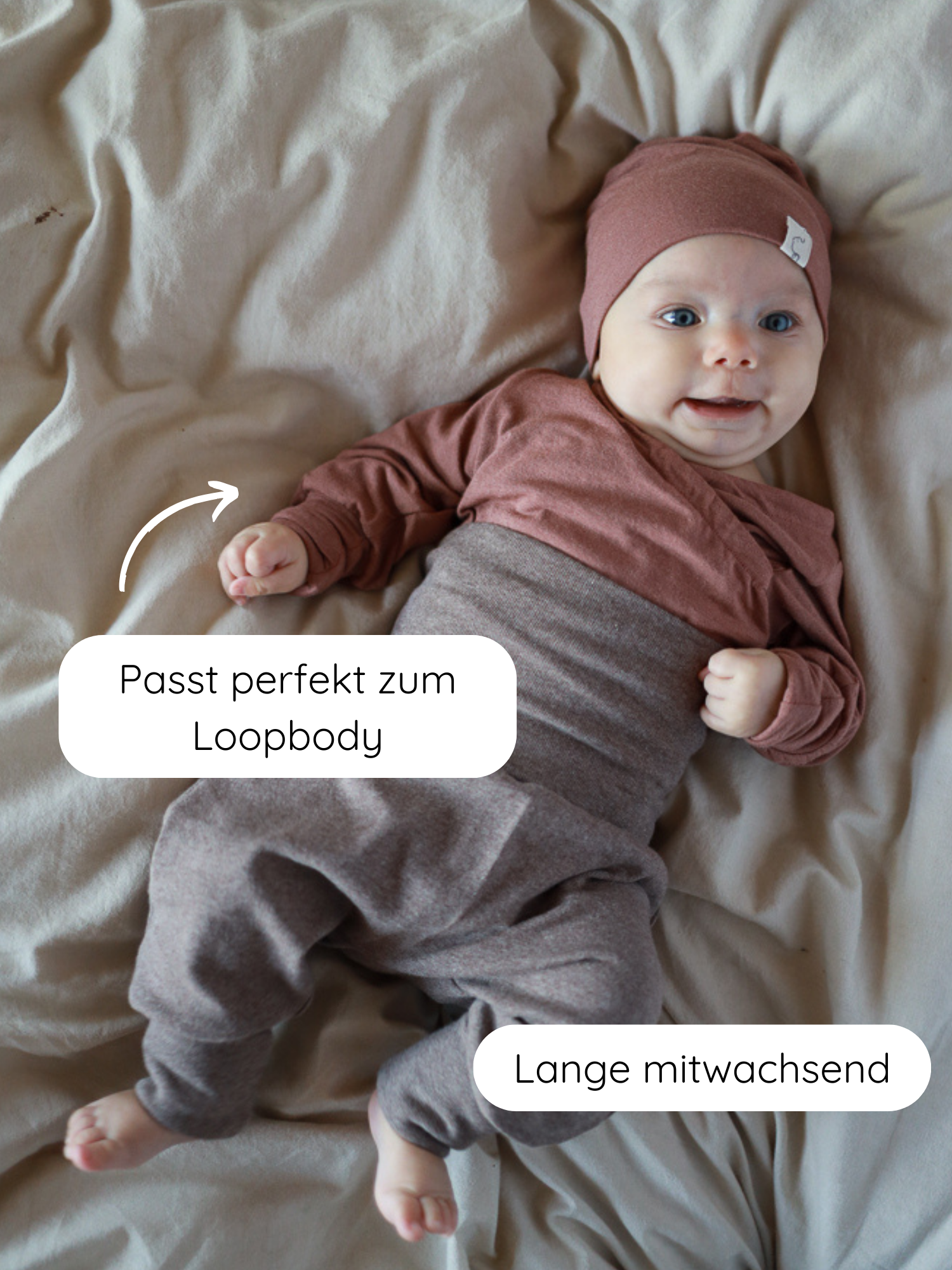 Baby liegt auf neutralem Untergrund in Babyknicker Feinstrick - Praline Meliert, bestehend aus weichem Jersey-Set mit Wickeloberteil, lockerer Hose und Beanie. Overlay-Texte: „Passt perfekt zum Loopbody“ und „Lange mitwachsend“.