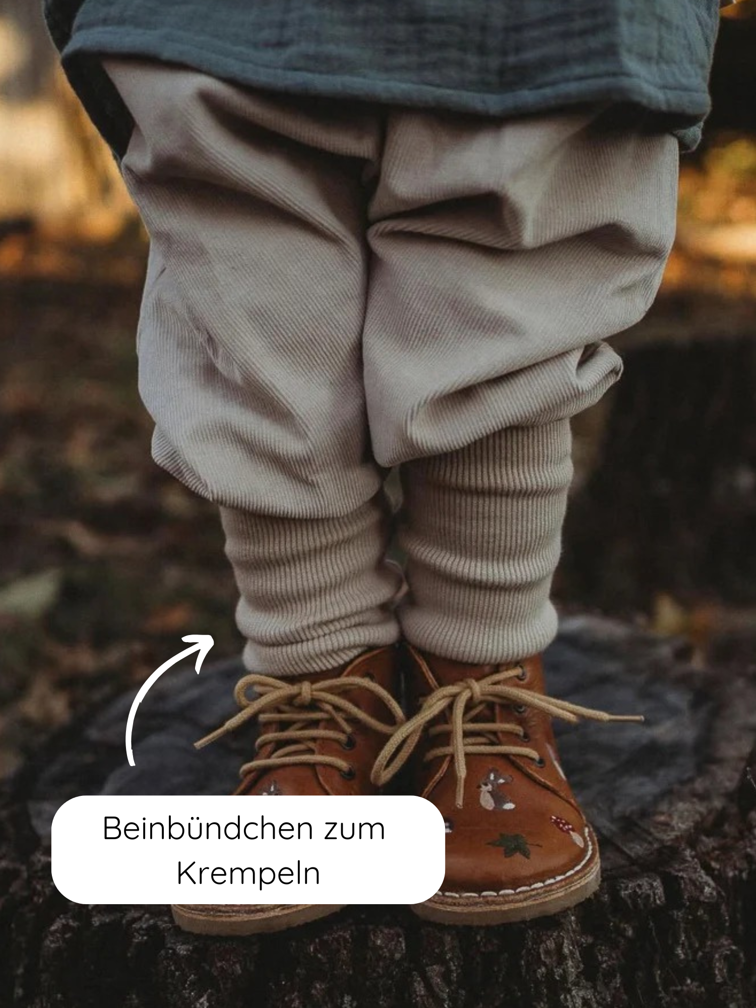 Knickerbocker Feincord - Sand: Ein Kind trägt beige Cord-Knickerbocker mit gerafften Beinen und braunen Lederstiefeln auf einem Baumstumpf, ideal für aktive Abenteuer in herbstlicher Umgebung.