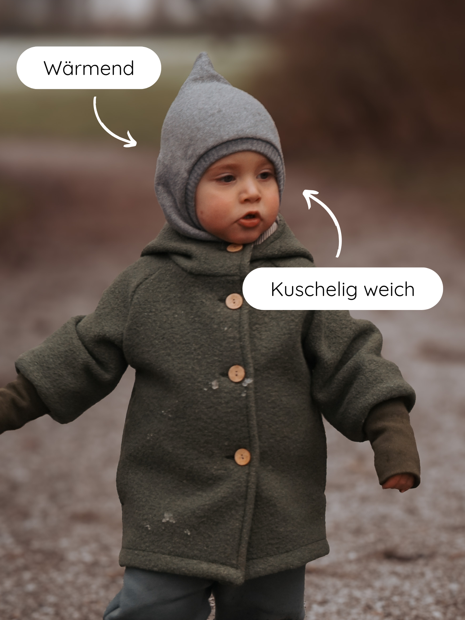 Kleinkind steht auf einem Kiesweg in einem Schlupfmütze Strick - Maus, einer grauen, weichen Wollmütze, die wärmt und kuschelig weich ist. Perfekt für Schutz vor Wind und Kälte.