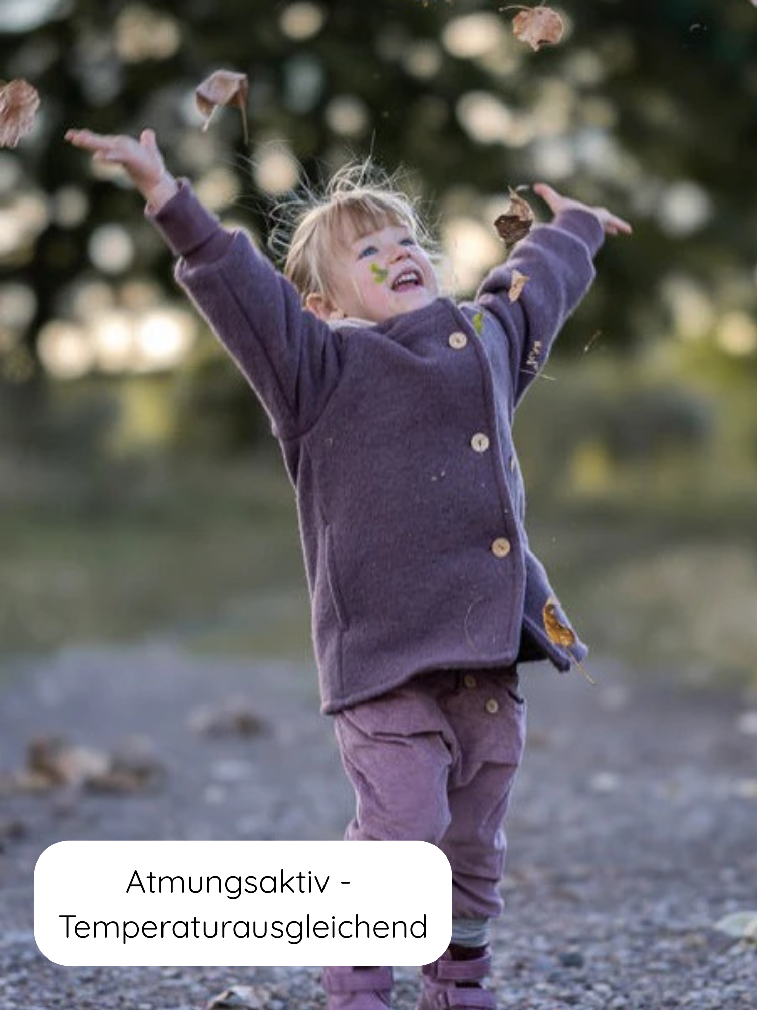 Kleinkind wirft Herbstblätter in die Luft, gekleidet in eine Wichteljacke Wollwalk - Malve. Die Jacke ist atmungsaktiv, temperaturausgleichend und ideal für Herbst, Frühling und Winter.